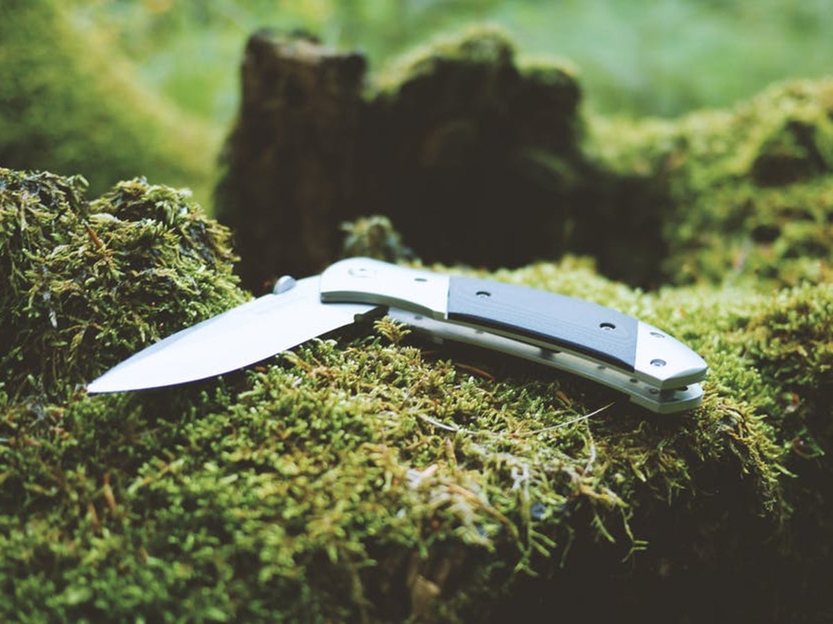 Three folders on a tailgate, clips already set. One knife, one pocket.