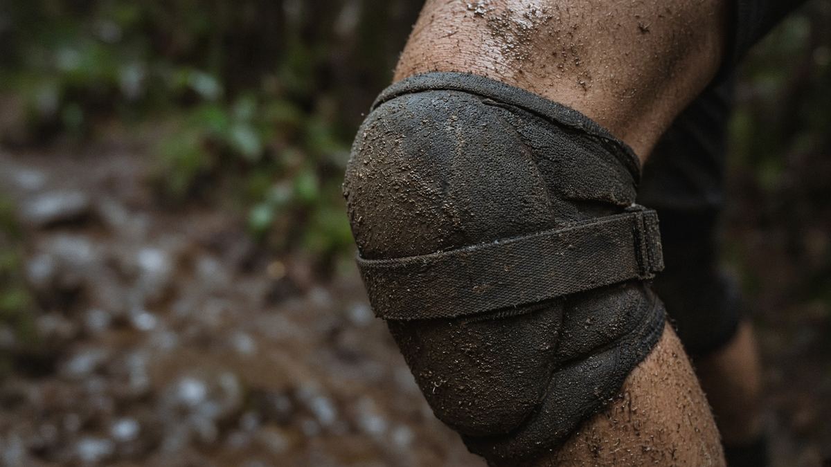 A strap still tight after a muddy descent is the pad. A DH render on a green trail is the ad.