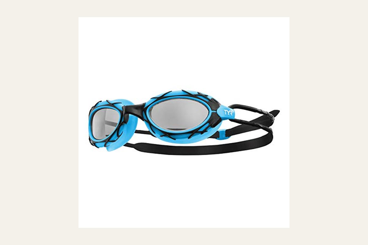 TYR Nest Pro swim goggles in black and green, style LGNST-014, on a pool deck.