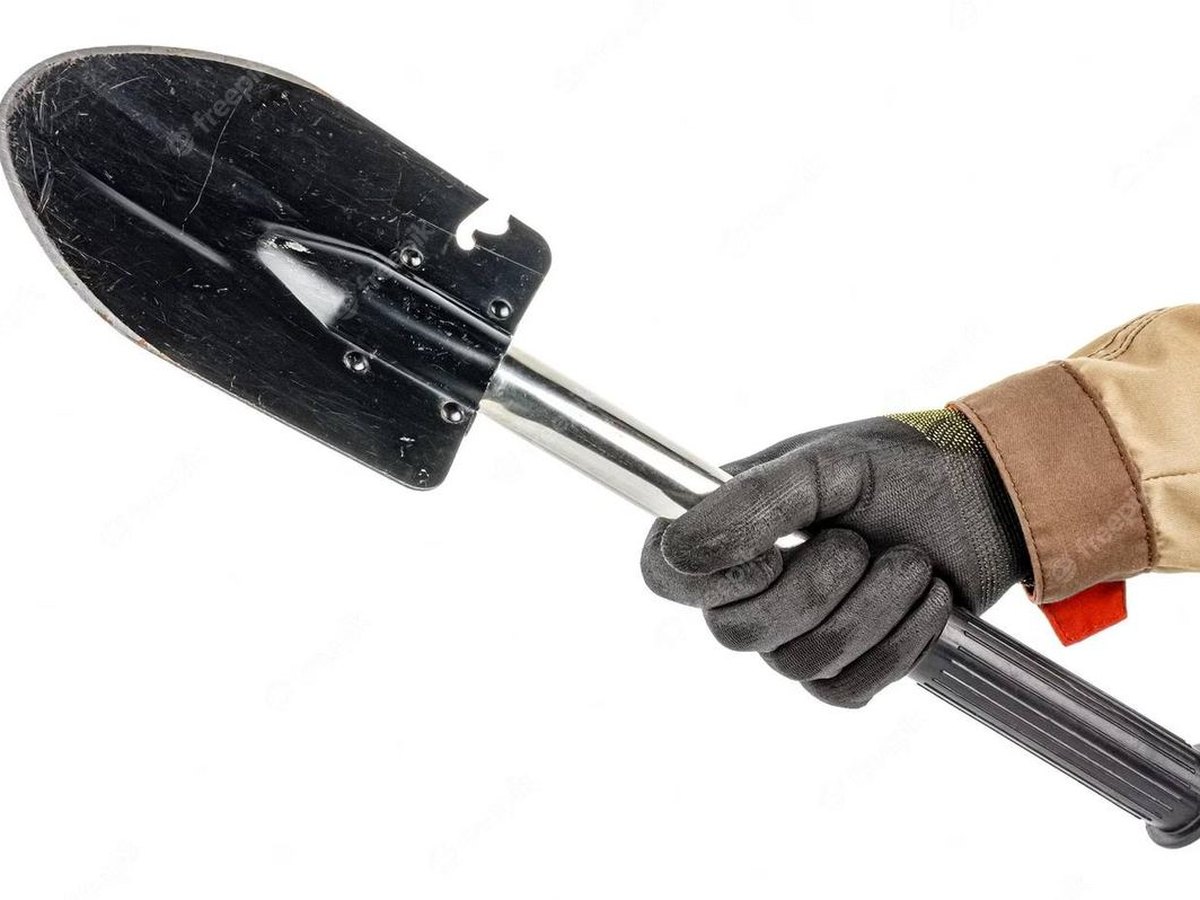 A folding e-tool beside a cathole and a fire ring. The lock is the tool.